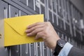 Close up of hand putting the yellow letter into the mailbox